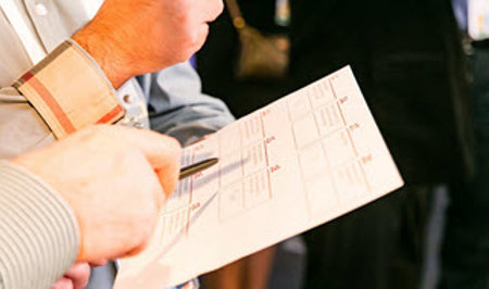 A person pointing a pen at a report paper
